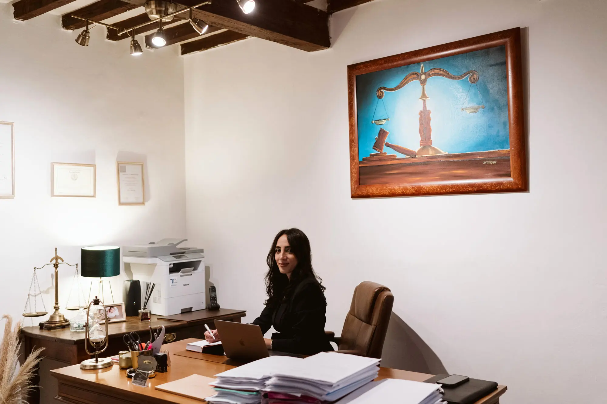 Lo studio legale di Pistoia con soffitto a travi in legno, dove Ada Alia lavora alla scrivania