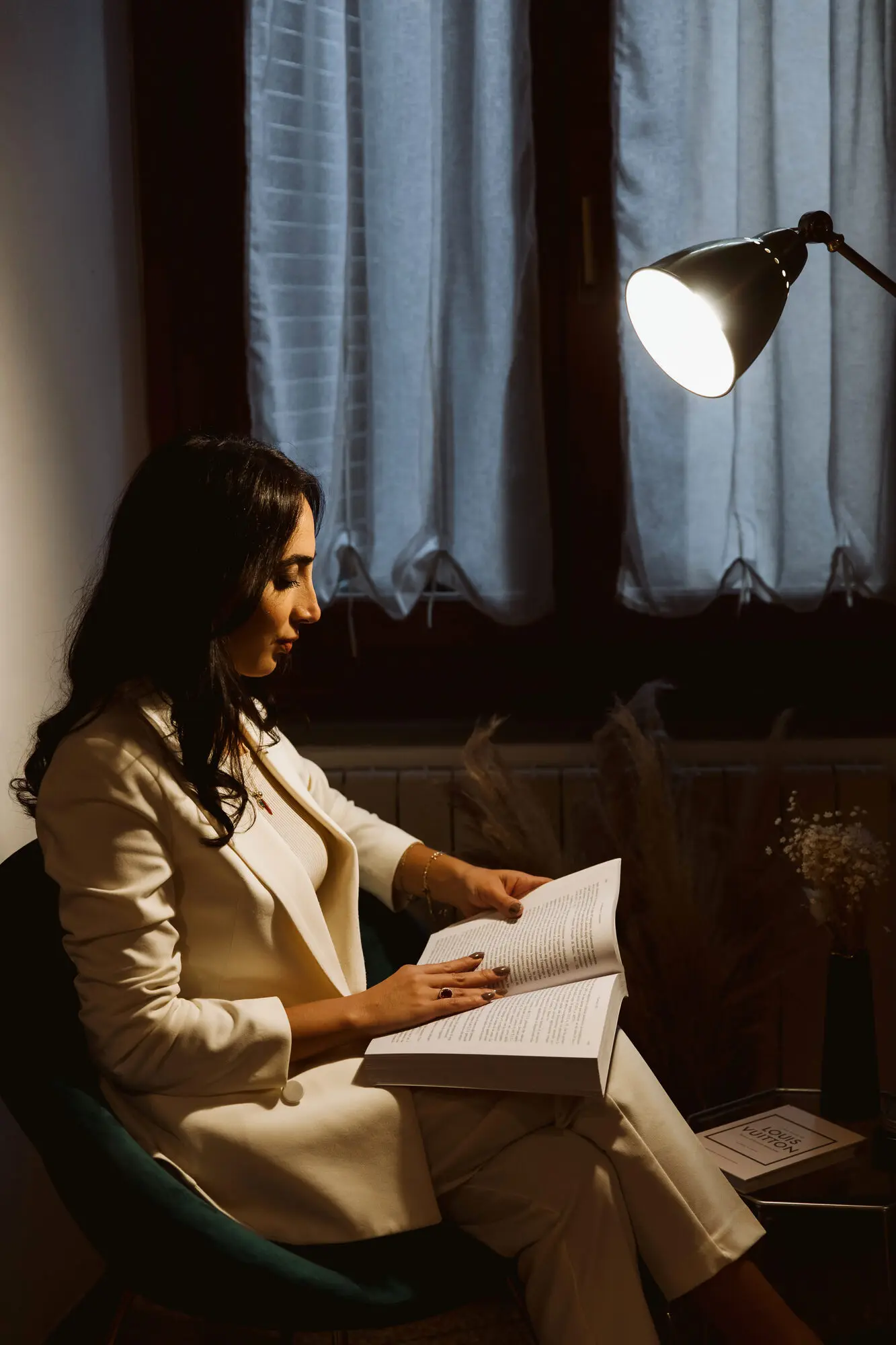 Ada Alia legge un fascicolo accanto alla finestra dello studio, alla luce di una lampada